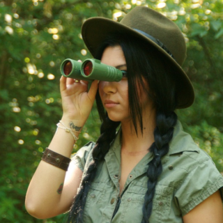 a lady tourist or hunter using binoculars
